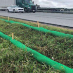 Lining a roadside area with compost filter sock to prevent erosion.