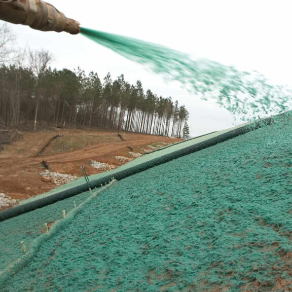 Hydraulic application of paper and wood mulch to large dirt area.