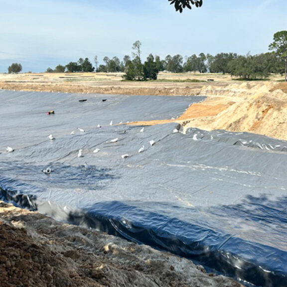 Black geomembrane panels on sandy worksite.