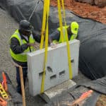 Construction workers guiding a porous precast Twall into position