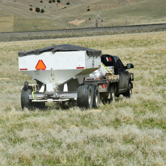 Truck and cart applying Nutrfix fertilizer on 10 acres of pastureland to enhance bison foraging.