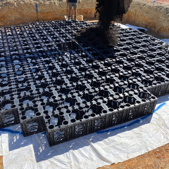 Backfilling UrbanForest soil cells with dirt to support tree root growth.