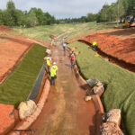 Landscape architects and contractors installing hard armor along channel slope for erosion control.