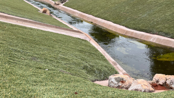 Hydroturf vegetated with grass on channel slopes for stabilization.