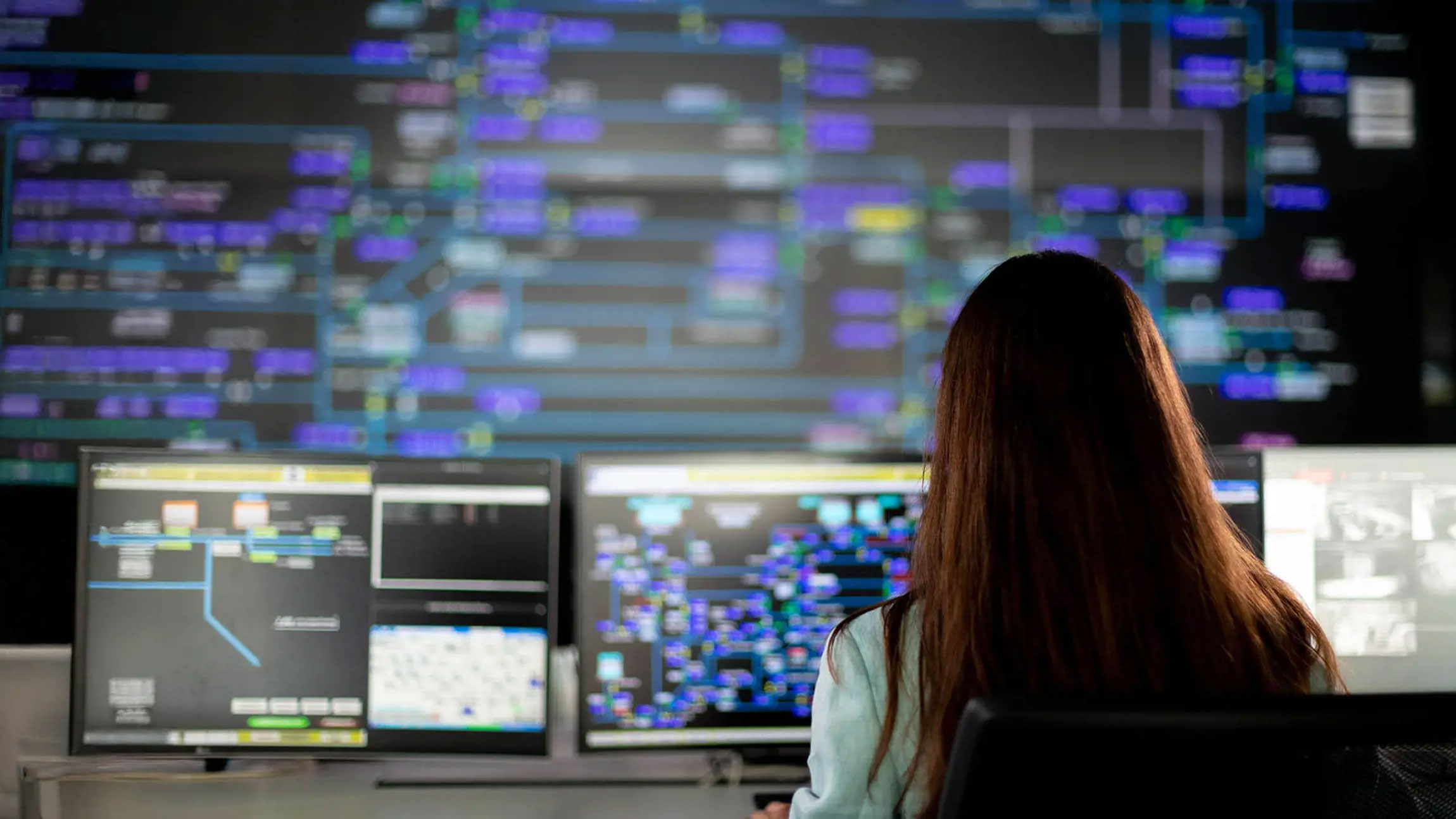 Woman at computer desk showing utility mapping data.