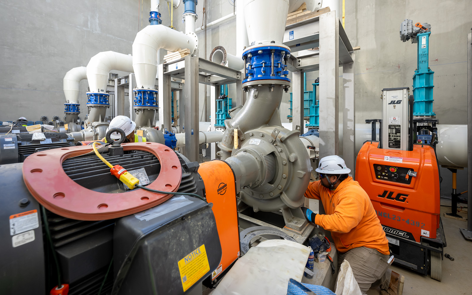 Man in orange working on pump station pipes