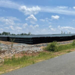 Stacked and organized black HDPE corrugated pipe on large job site.