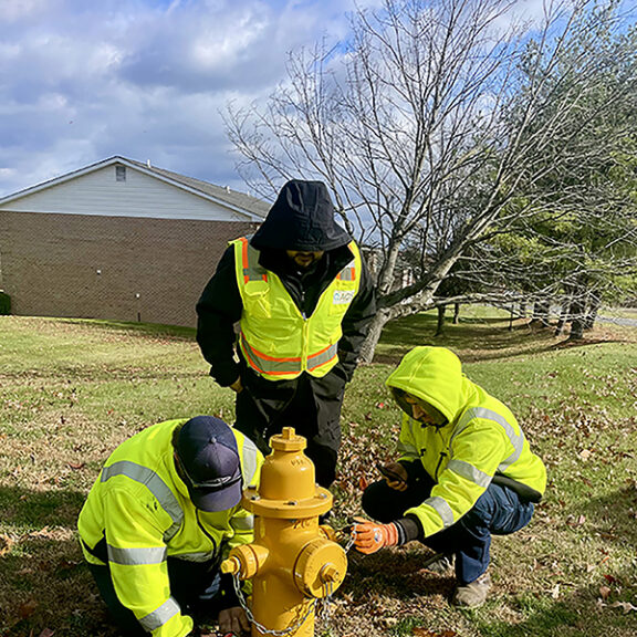 3 utility workers at a hydrant installing AQS leak detection sensors.