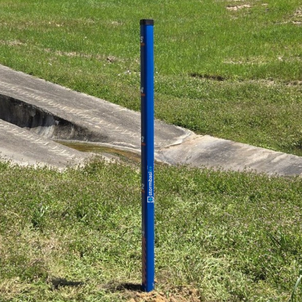 Blue depth marker post in stormwater runoff area with large numbers.