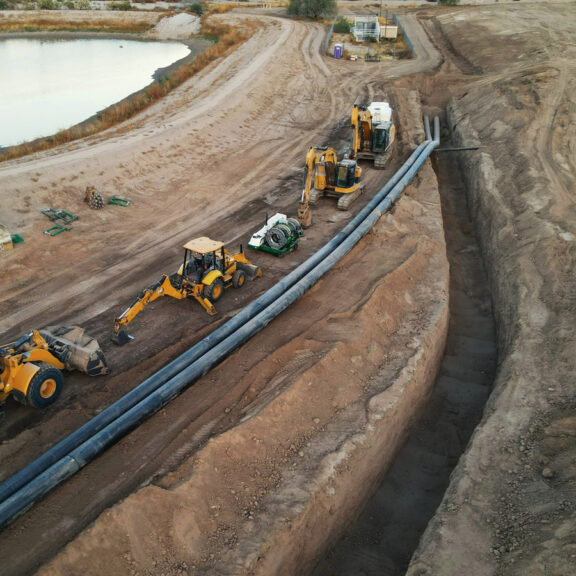 Large trench with HDPE lined by 4 excavators.