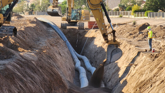 HDPE pipe in large trench being covered by dirt.