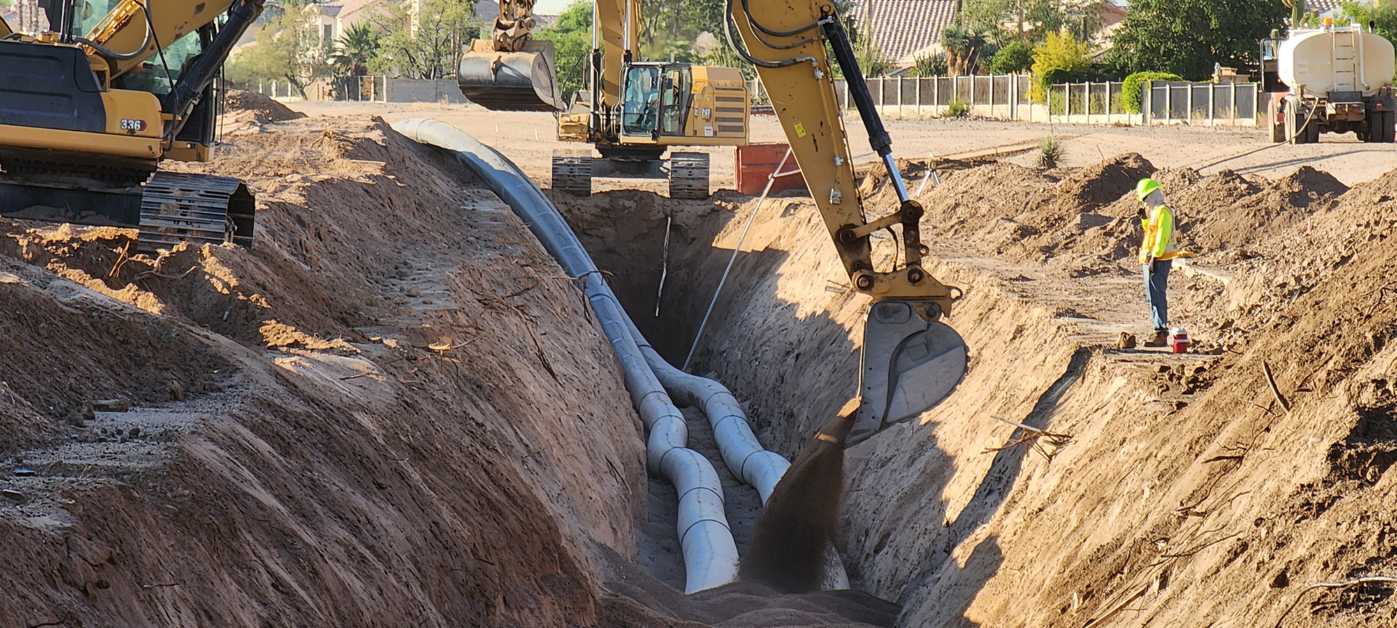 HDPE pipe in large trench being covered by dirt.