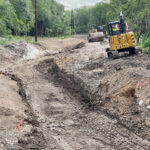 Mini excavator clearing drainage channel