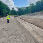 Construction workers walking along dirt drainage channel