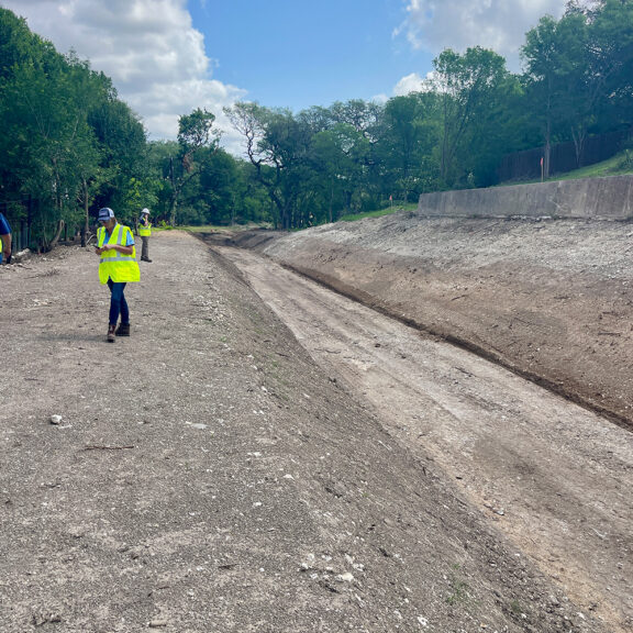 Construction workers walking along dirt drainage channel