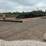 Installing large rolls of geogrid above crushed concrete for parking lot.