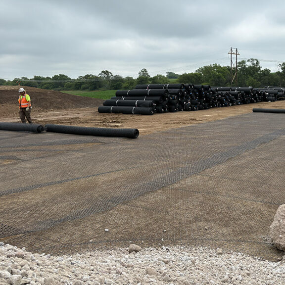 Installing large rolls of geogrid above crushed concrete for parking lot.